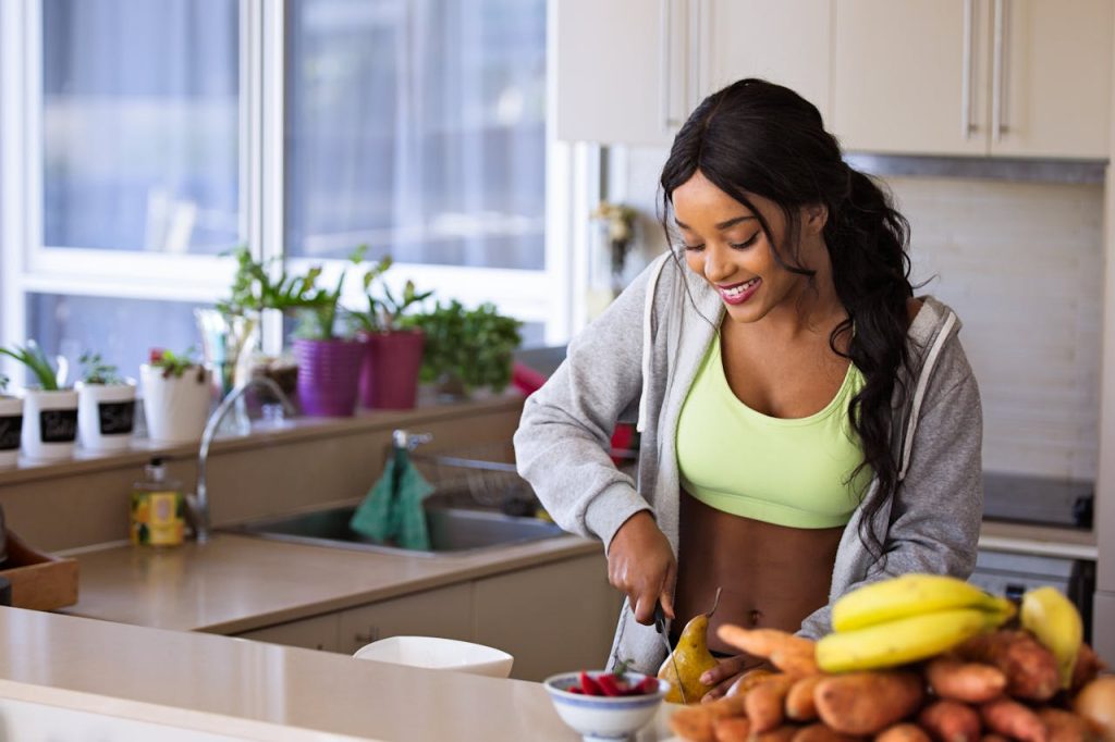 woman-slicing-gourd-1153369 Smiling woman preparing fresh fruit in a sunlit kitchen, embodying a healthy lifestyle.